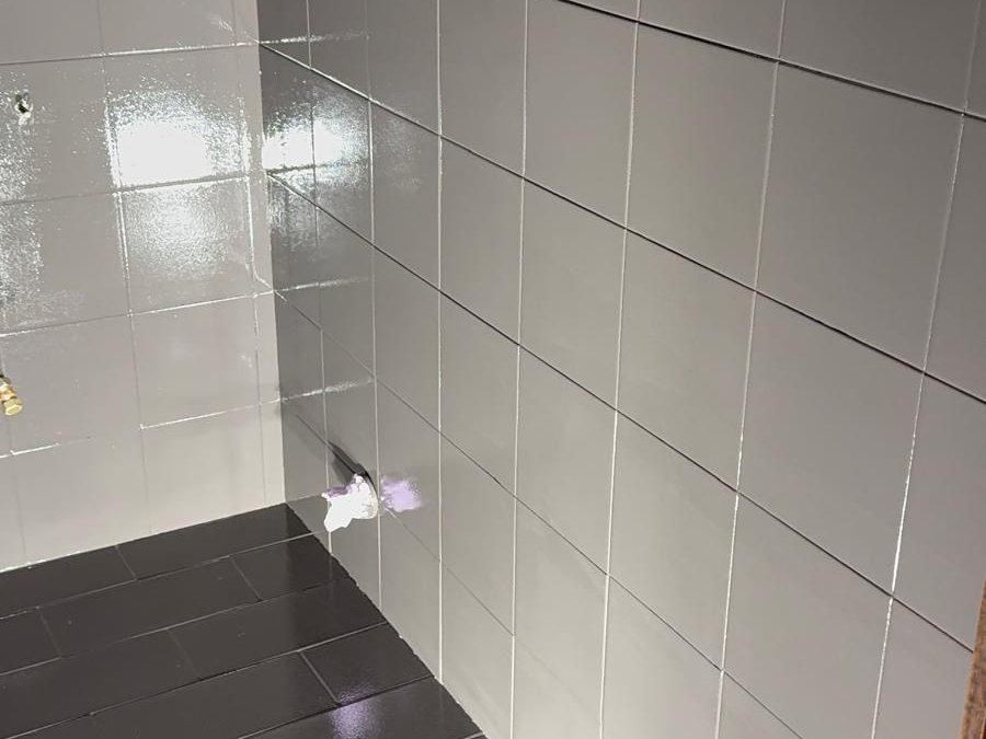 Angolo di un locale con le piastrelle delle pareti riverniciate grigio chiaro e il pavimento piastrellato antracite