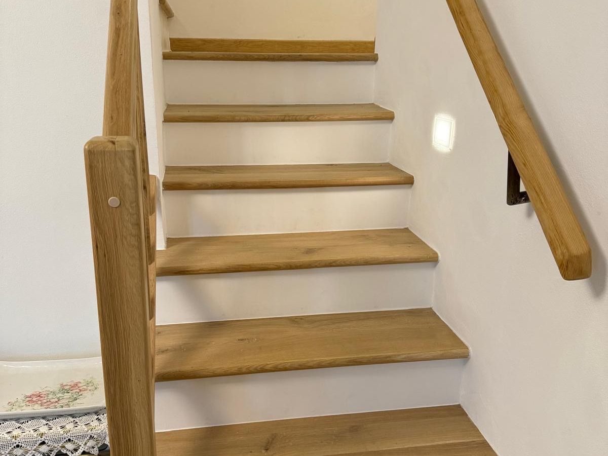 Scala interna con gradini in legno di rovere, alzate bianche e parapetto con corrimano in legno chiaro