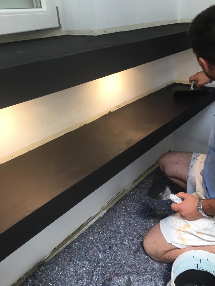 Decoratore stende a spatola la finitura in resina scura su una mensola