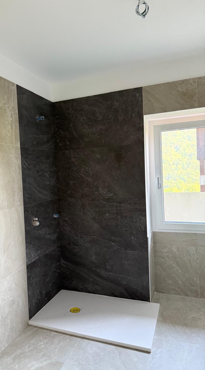 Bagno in ristrutturazione con rivestimento a grandi lastre e piatto doccia