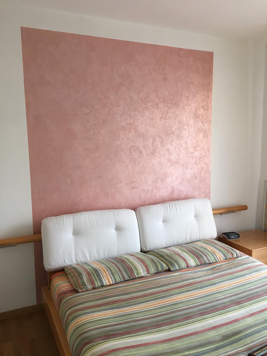 Camera da letto con parete decorata in rosa perlato dietro la testata del letto