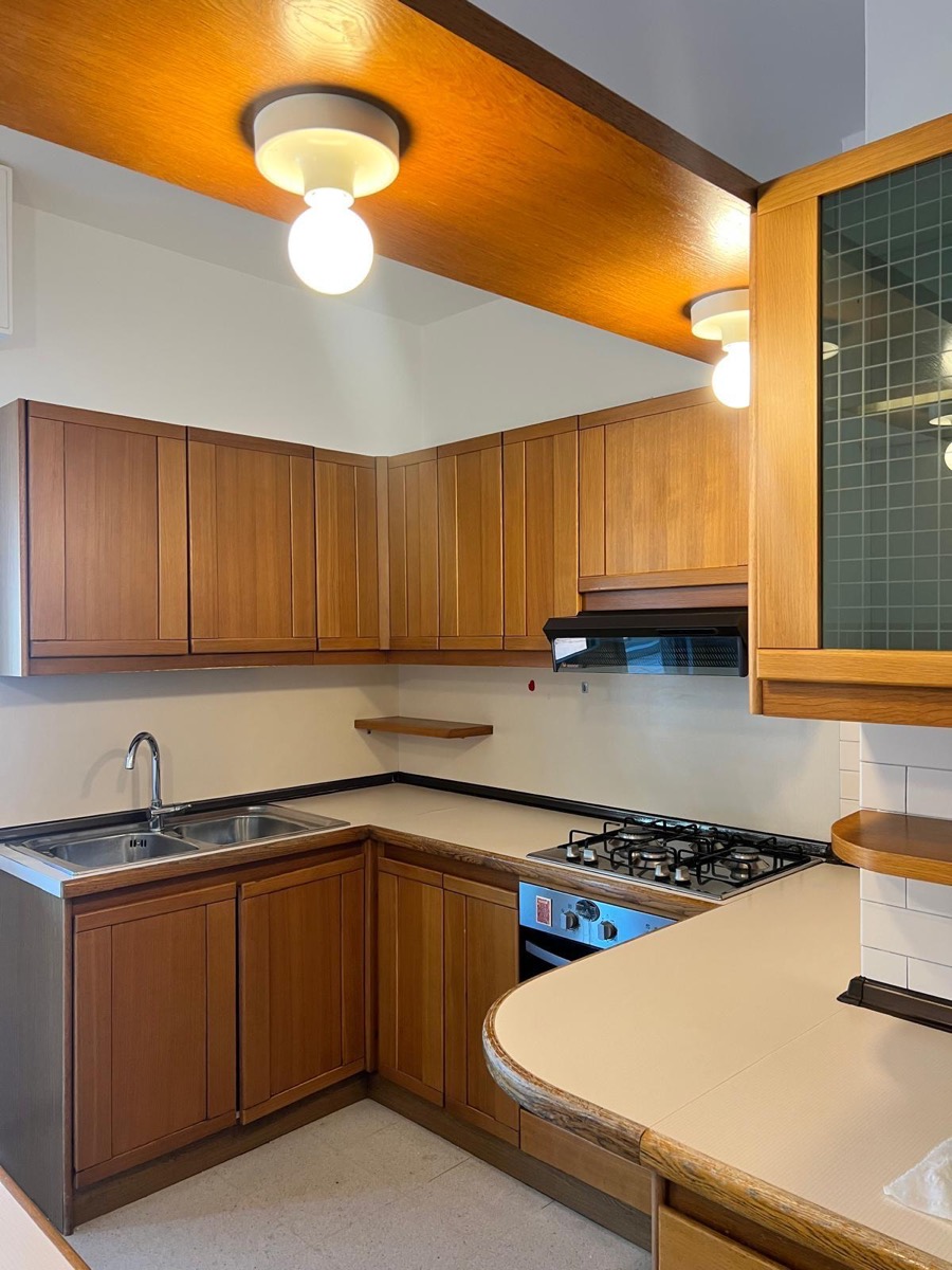 Cucina con mobili in legno chiaro e pareti e soffitto appena tinteggiati di bianco