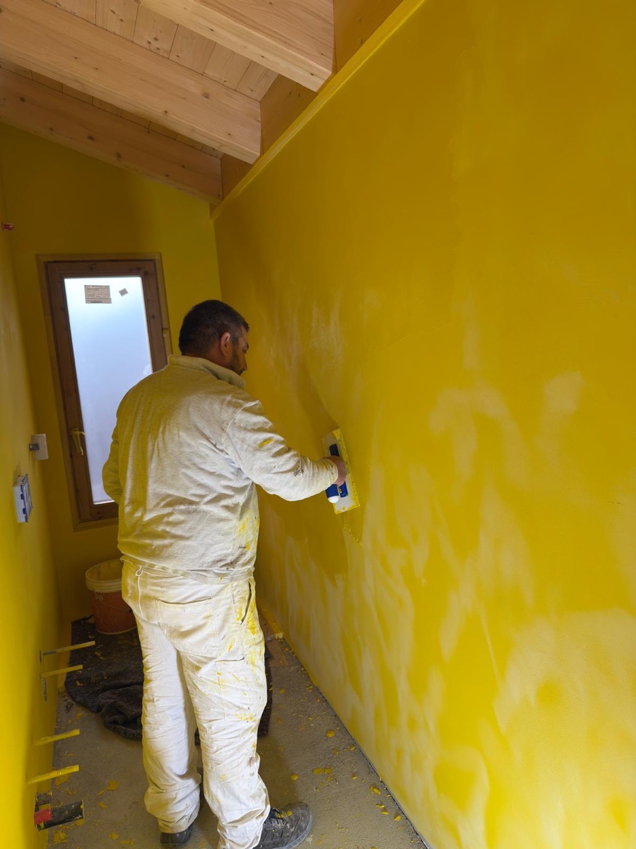 Decoratore applica a frattazzo una finitura decorativa gialla su parete