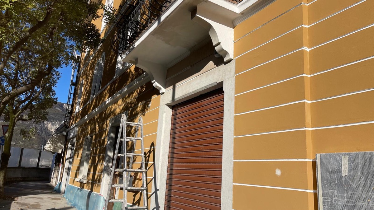 Facciata esterna tinteggiata giallo ocra con fasce bianche e cornici chiare, ripresa in prospettiva