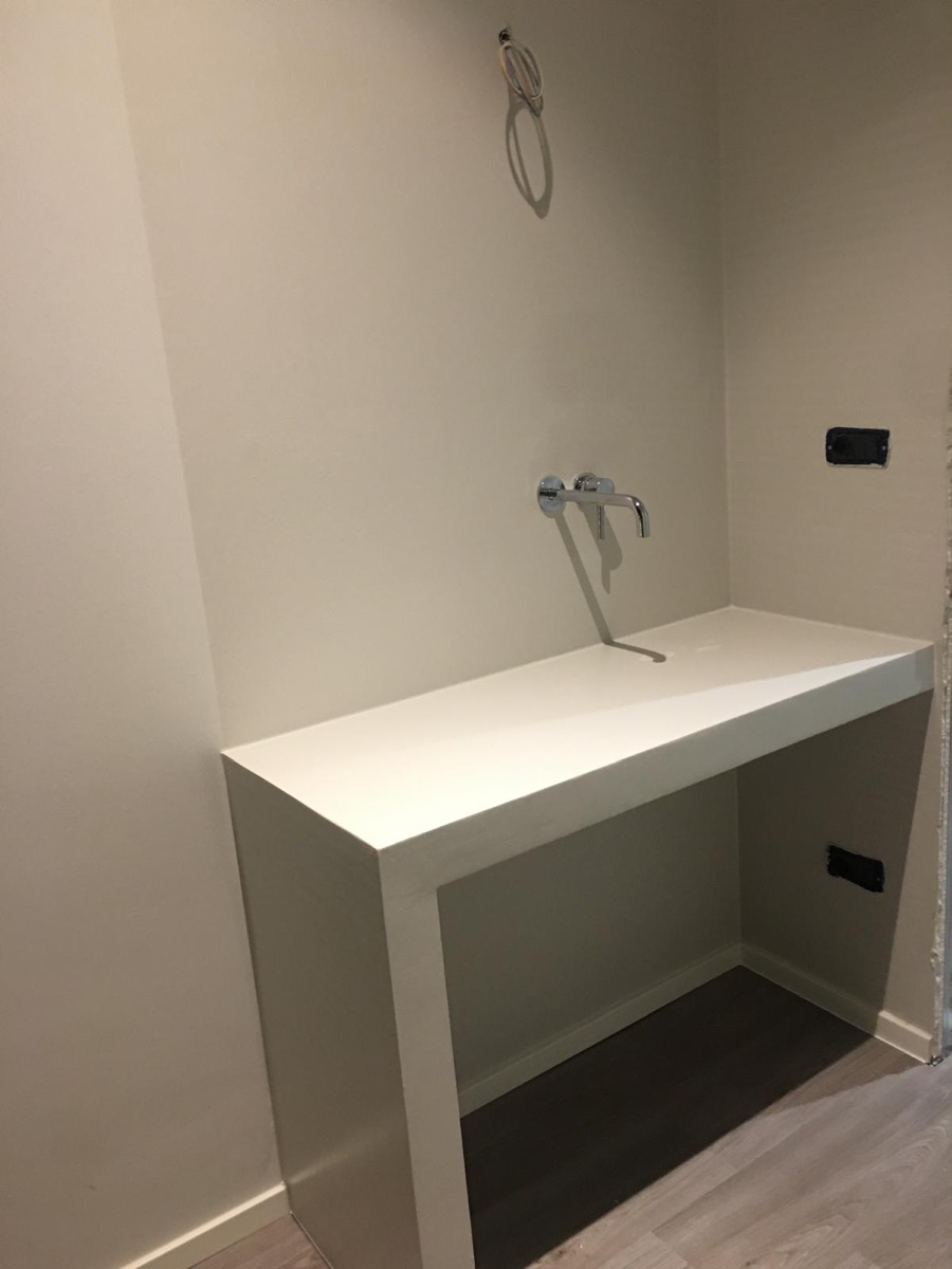 Nicchia bagno con piano lavabo continuo bianco, rubinetto a muro cromato e pareti color tortora