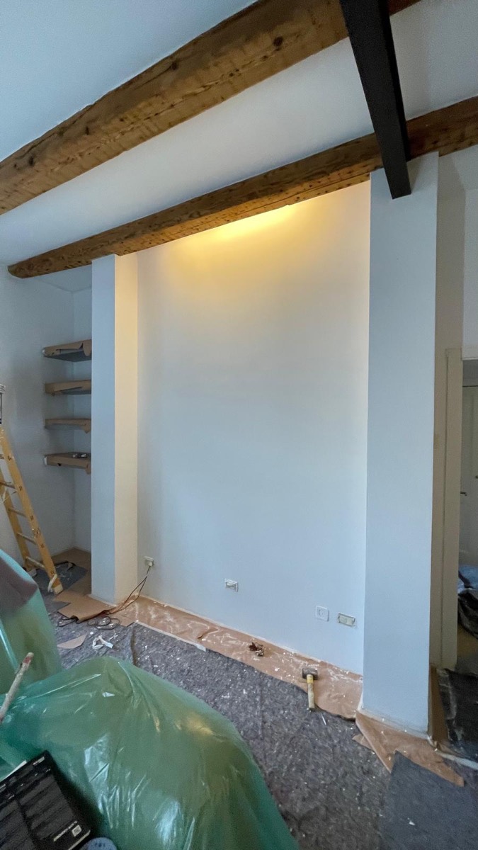 Interno con nicchia e parete bianche appena tinteggiate sotto travi di legno a vista