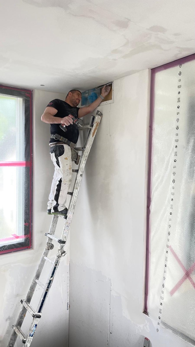 Posa di lastre in cartongesso all'angolo tra parete e soffitto, avvitatura dall'alto della scala