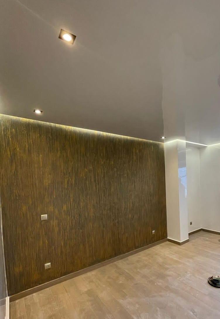Parete decorativa effetto materico bronzo con rigatura verticale, illuminata da luce radente
