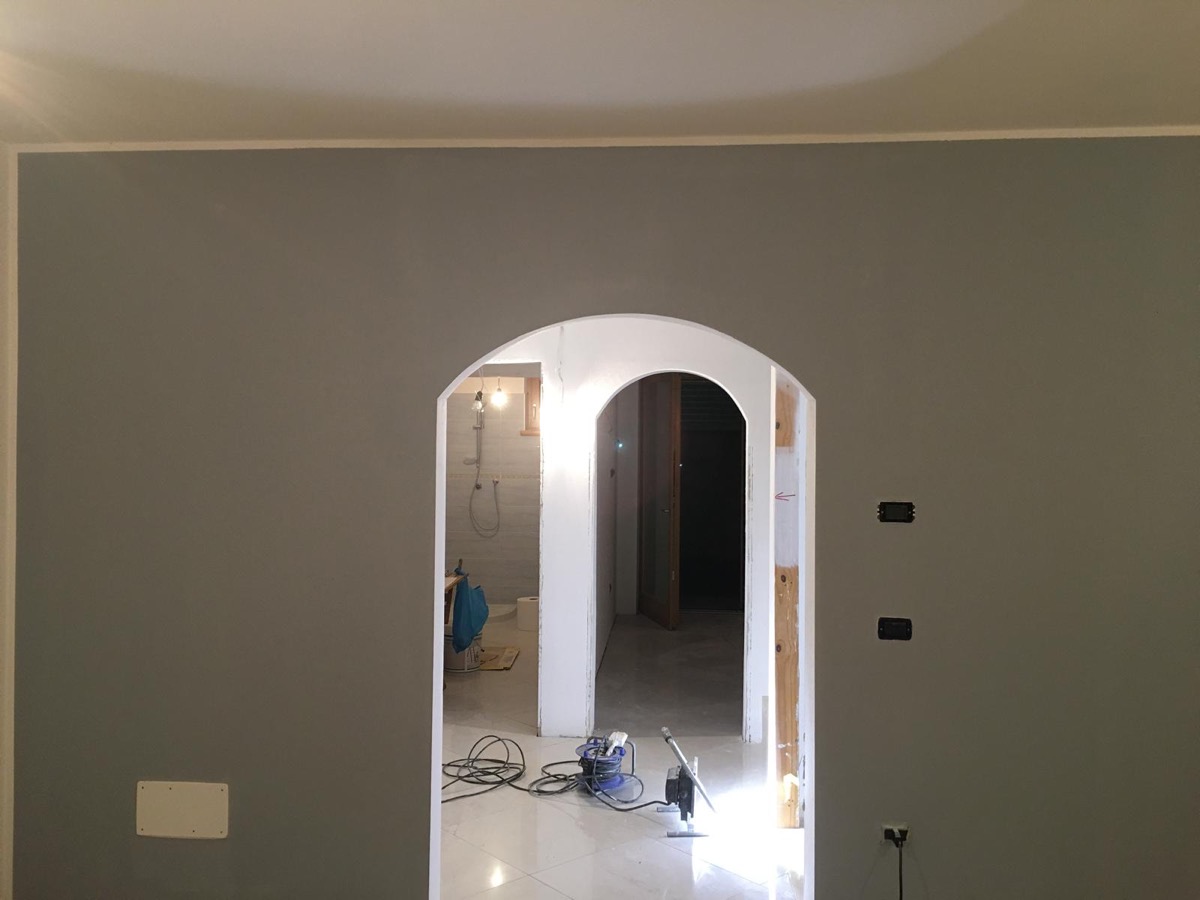 Parete interna tinteggiata grigio tortora con arco bianco appena rifinito