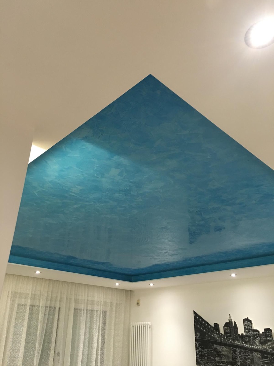 Soffitto interno con finitura spatolata azzurra e controsoffitto perimetrale con faretti accesi