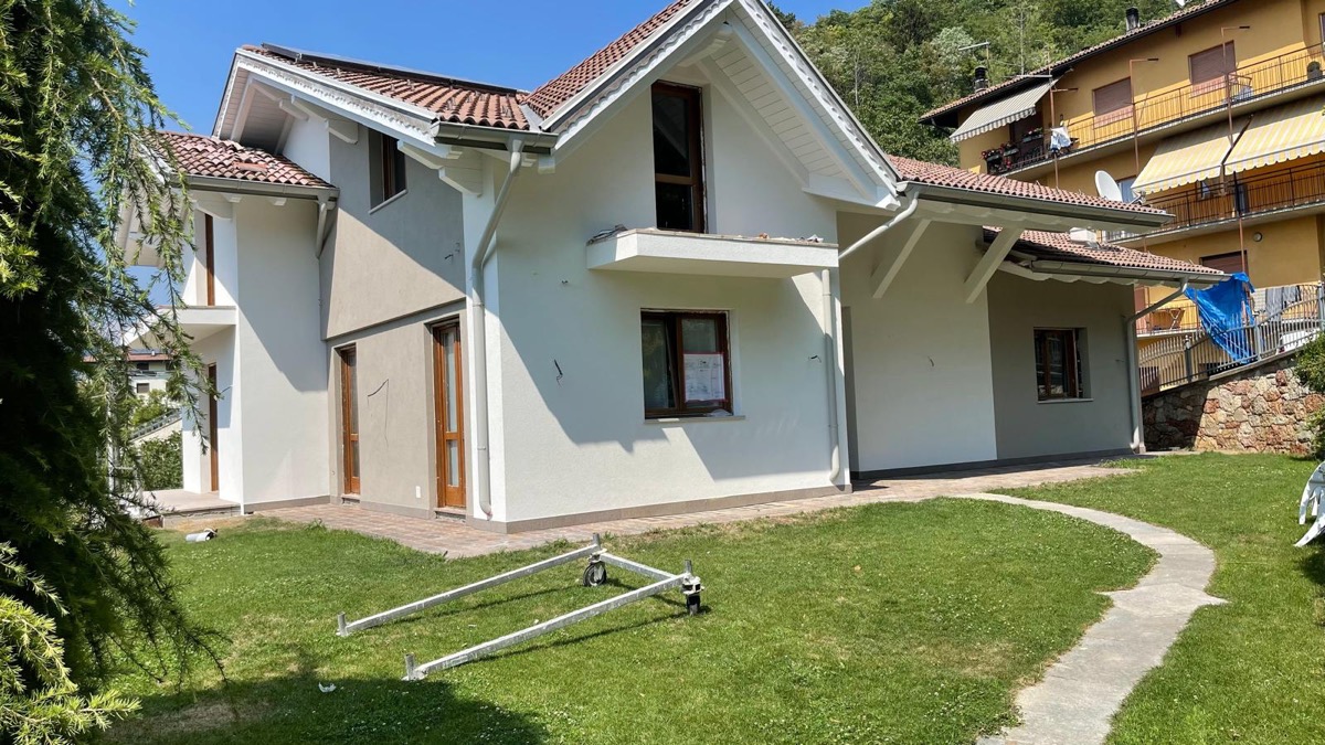 Villa con facciata appena tinteggiata in tonalita chiara, tetto in tegole e giardino con prato