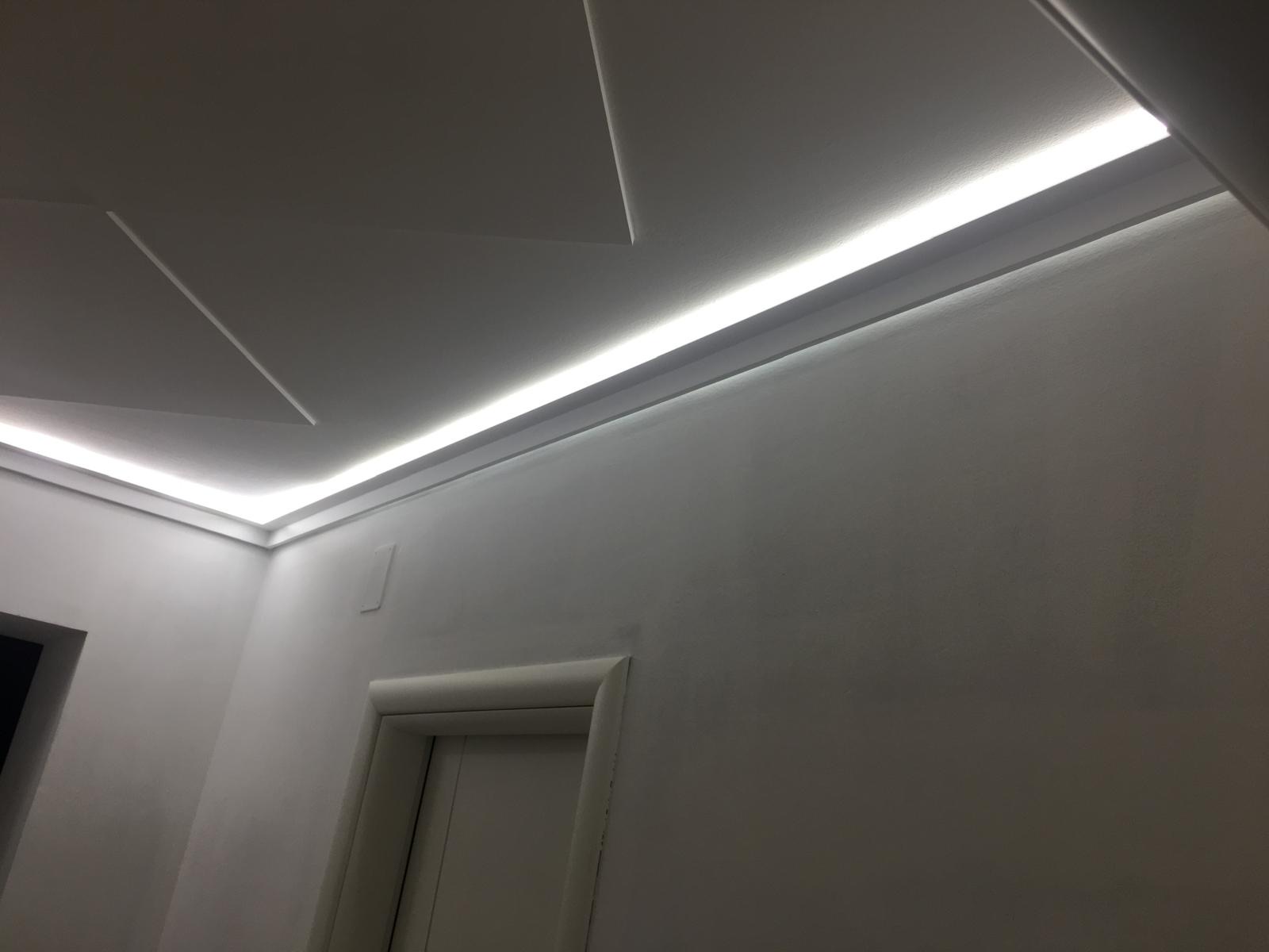 Controsoffitto in cartongesso con veletta perimetrale e striscia led accesa che illumina pareti bianche
