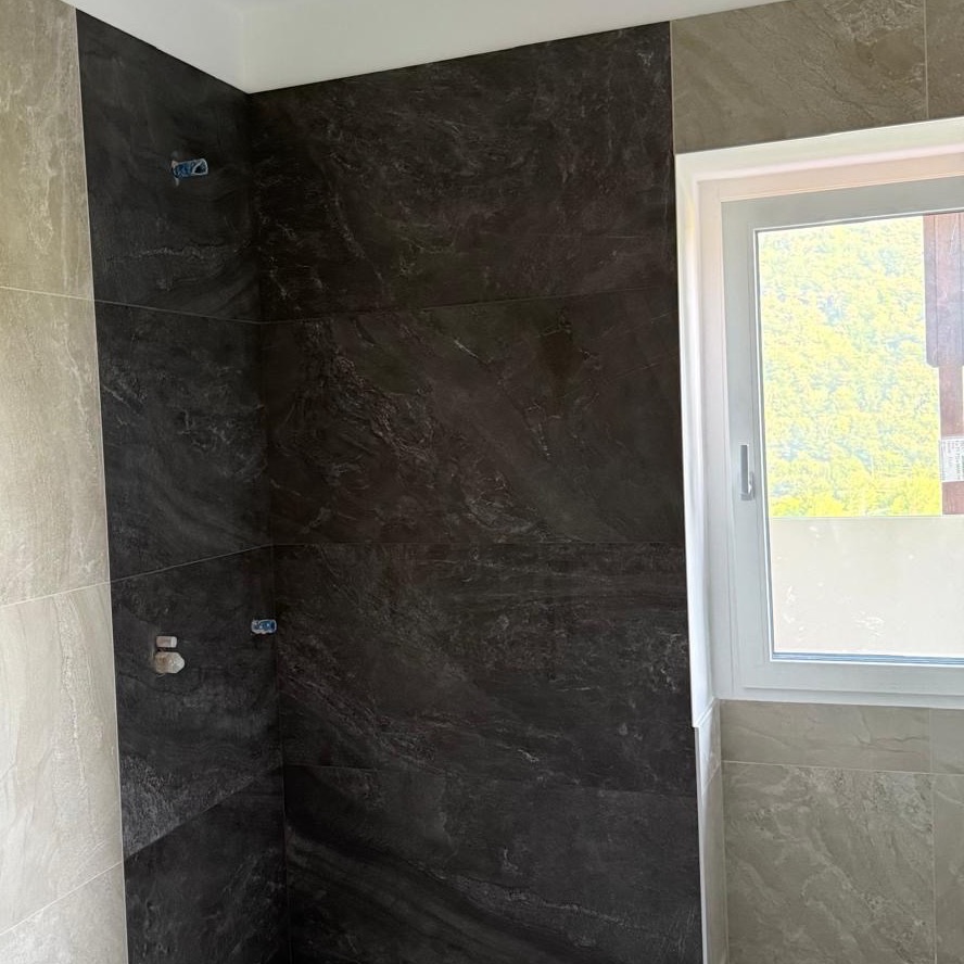Bagno in ristrutturazione con rivestimento a grandi lastre e piatto doccia