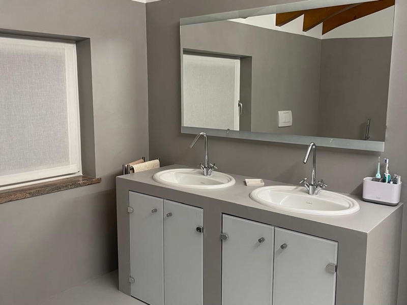 Mobile bagno grigio con due lavabi in ceramica, specchio a filo e pareti grigie continue