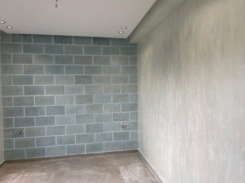 Stanza finita con parete decorata a finti conci verde-grigio e parete attigua effetto spatolato chiaro