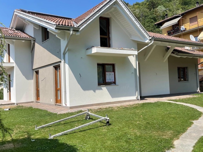 Villa con facciata appena tinteggiata in tonalita chiara, tetto in tegole e giardino con prato